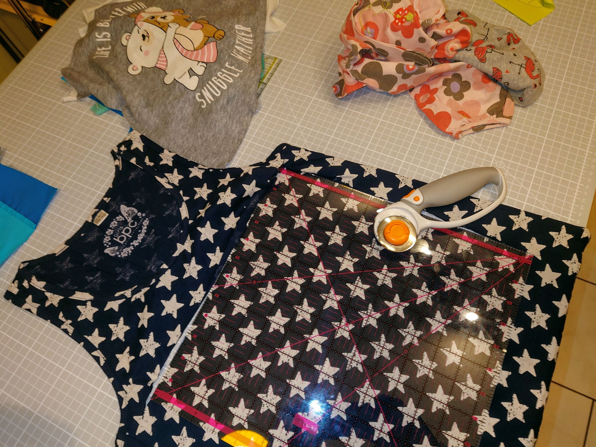 Ein marineblaues Kinderkleid mit weißen Sternen bedruckt. Das Kleid liegt flach auf einer Schneidematte mit einem Rollschneider und einem Lineal. 