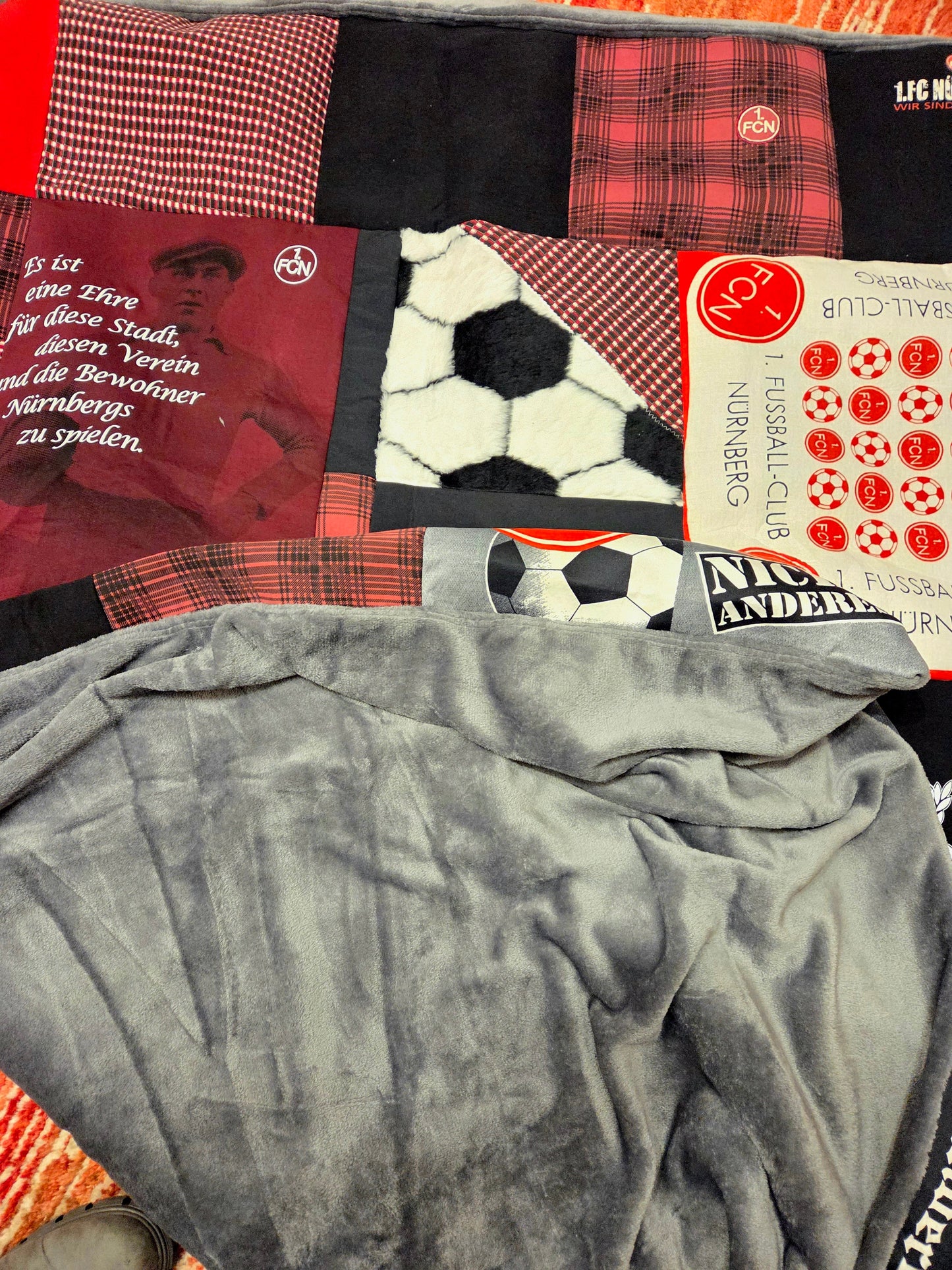 Eine Patchworkdecke mit Fußballmotiven und einer grauen Fleece-Rückseite.