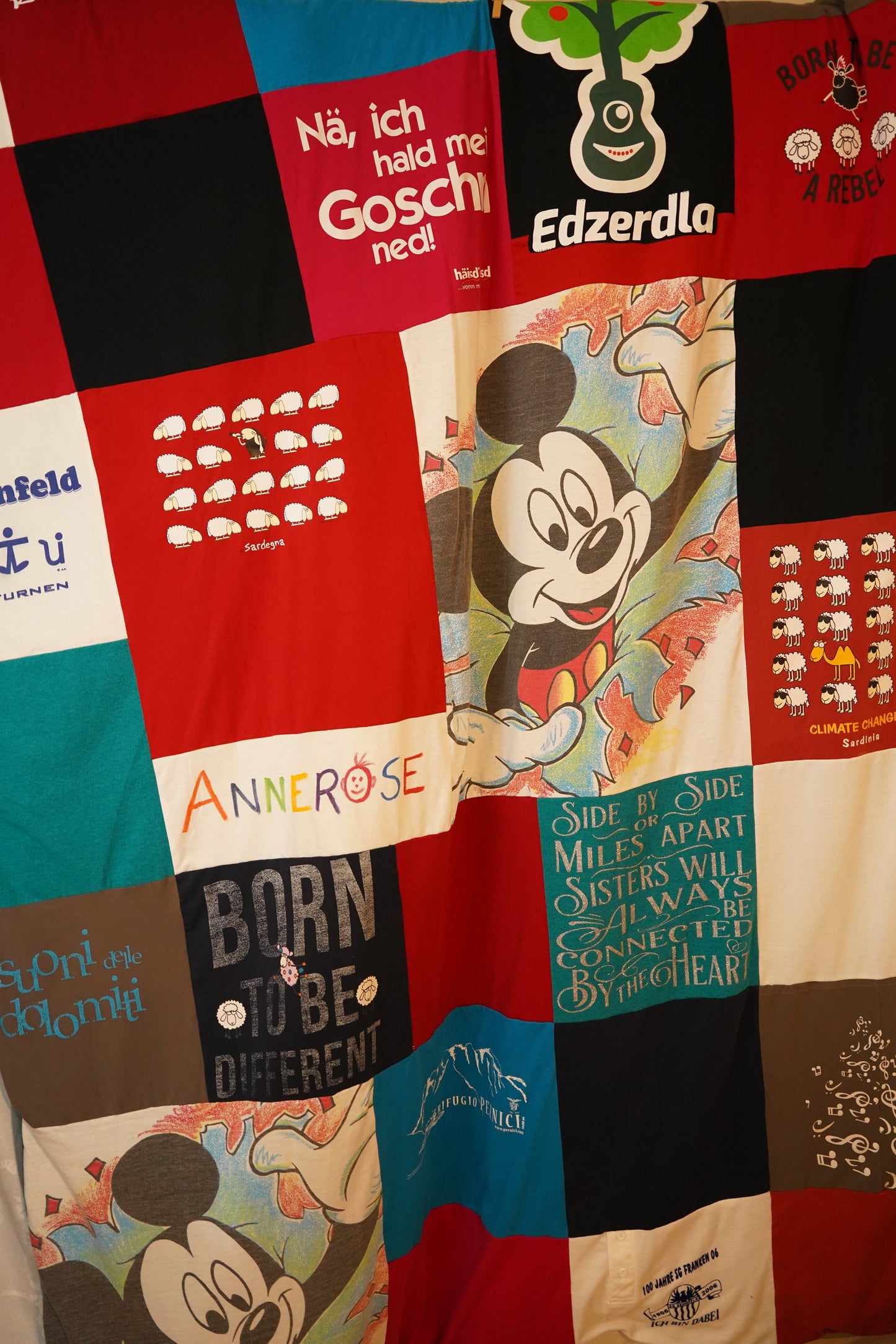 Eine Patchwork-Decke aus verschiedenen T-Shirts. Die Decke zeigt eine Vielzahl von Farben, Mustern und Texten.