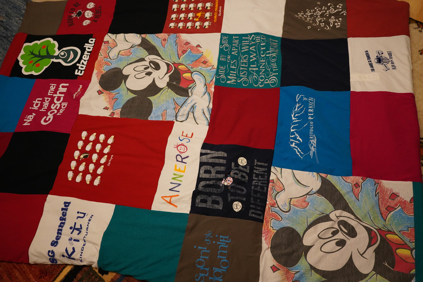 Eine Patchwork-Decke aus verschiedenen T-Shirts. Die Decke zeigt eine Vielzahl von Farben, Mustern und Texten.