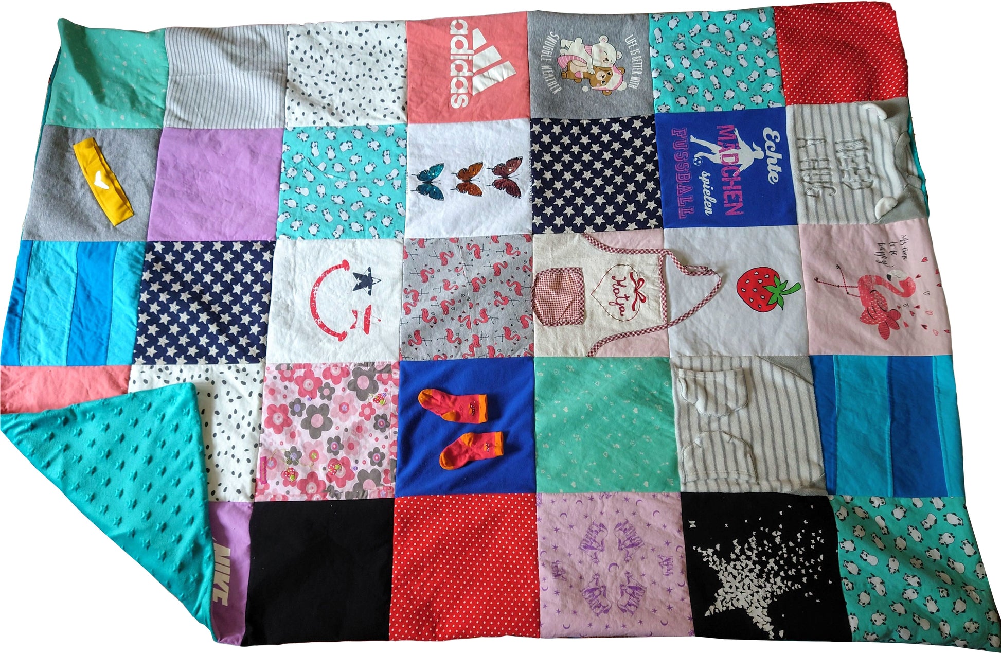 Eine Patchwork-Decke aus verschiedenen Stoffresten, mit einer Vielzahl von Farben, Mustern und Designs. Die Decke enthält einen blauen Stoff mit weißen Sternen, einen rosa Stoff mit weißen Blumen, einen roten Stoff mit weißen Punkten und einen blauen Stoff mit weißen Streifen. Die Decke zeigt auch eine Vielzahl von gestickten Designs, darunter ein Smiley, ein Schmetterling und ein Flamingo.
