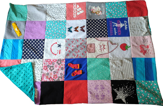 Eine Patchwork-Decke aus verschiedenen Stoffresten, mit einer Vielzahl von Farben, Mustern und Designs. Die Decke enthält einen blauen Stoff mit weißen Sternen, einen rosa Stoff mit weißen Blumen, einen roten Stoff mit weißen Punkten und einen blauen Stoff mit weißen Streifen. Die Decke zeigt auch eine Vielzahl von gestickten Designs, darunter ein Smiley, ein Schmetterling und ein Flamingo.